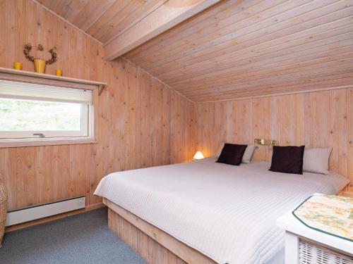 ブロックフスにあるHoliday home Blokhus Xの木製の部屋にベッド1台が備わるベッドルーム1室があります。