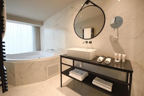 a bathroom with a tub and a sink and a mirror at Hôtel La Maison Bord'eaux in Bordeaux