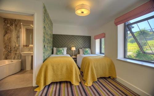 a bedroom with two beds and a tub and a window at Denbies Vineyard Hotel in Dorking