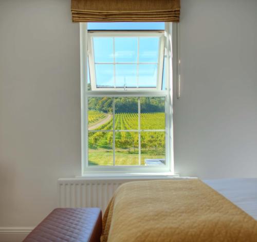 a bedroom with a bed and a window with a view at Denbies Vineyard Hotel in Dorking