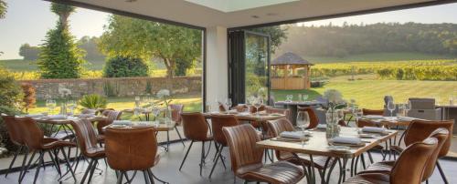 a dining room with tables and chairs and a large window at Denbies Vineyard Hotel in Dorking