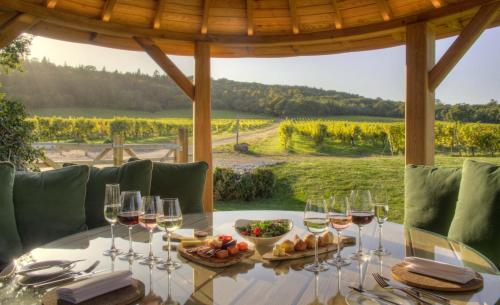 a table with glasses of wine and a view of a vineyard at Denbies Vineyard Hotel in Dorking