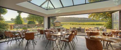 a dining room with tables and chairs and a large window at Denbies Vineyard Hotel in Dorking