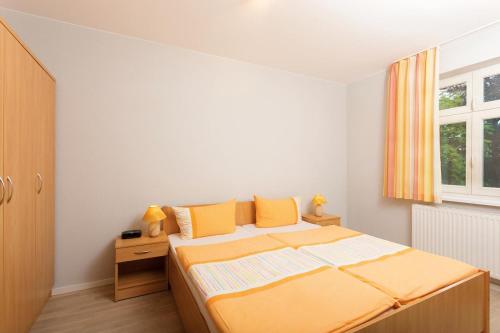 a bedroom with a bed with orange sheets and a window at Maisonetten Apartment in Rheinsberg