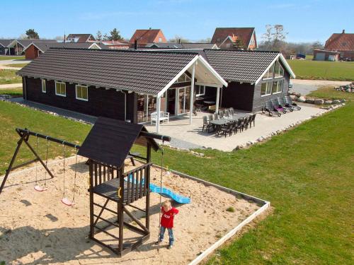 Ein kleiner Junge, der vor einem Spielplatz steht. in der Unterkunft 16 person holiday home in Sydals in Høruphav