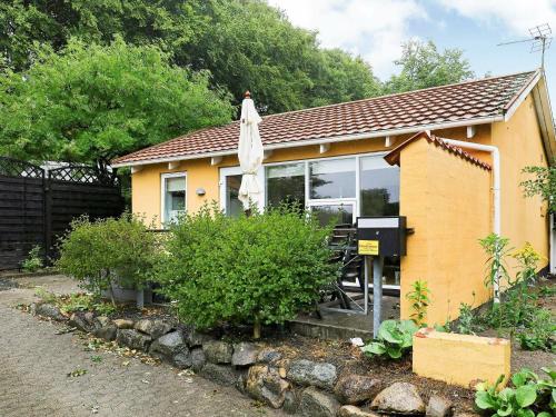 uma pequena casa amarela com uma mesa e um guarda-chuva em 4 person holiday home in Nyk bing M em Refshammer