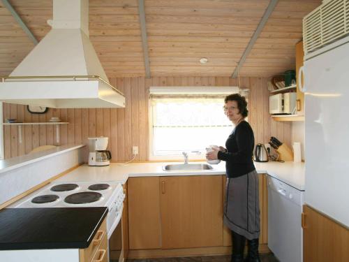 a woman standing in a kitchen with a sink at 8 person holiday home in Stege in Stege