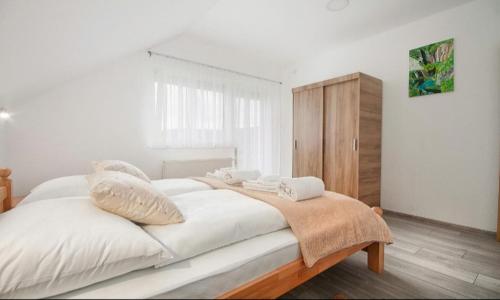 ein Schlafzimmer mit einem großen Bett mit weißer Bettwäsche und Kissen in der Unterkunft Apartment Josipa in Selište Drežničko