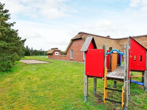 a playground in a yard next to a building at 12 person holiday home in Ulfborg in Husby