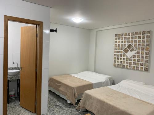 two beds in a room with a sink and a mirror at Locking's Lourdes 1 in Belo Horizonte
