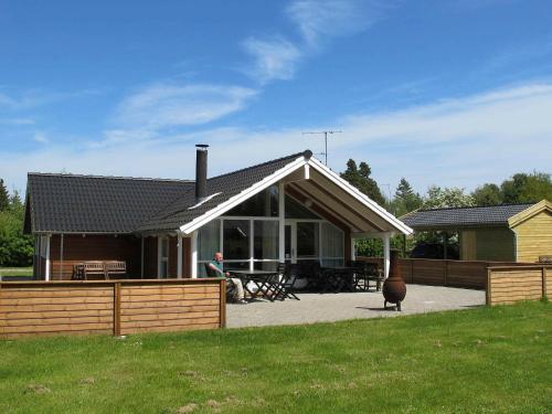 a house with a man sitting in front of it at 8 person holiday home in Idestrup in Marielyst