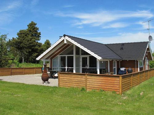 a small house with a wooden fence in front of it at 8 person holiday home in Idestrup in Marielyst