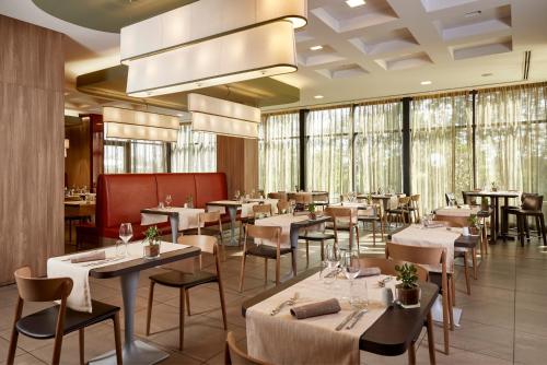 een restaurant met tafels, stoelen en ramen bij Blu Hotel Brixia in Castenedolo