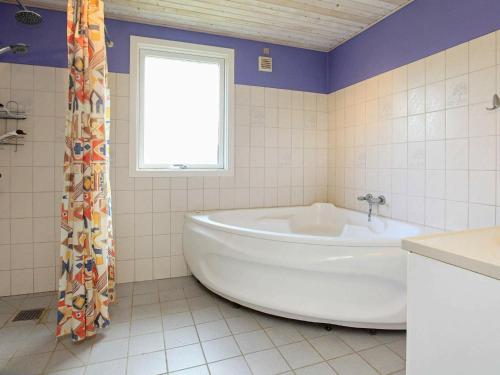 a white tub in a bathroom with a window at 8 person holiday home in Dannemare in Dannemare