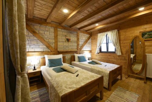 a bedroom with two beds in a log cabin at Ethno Houses Plitvice Lakes Hotel in Plitvica selo