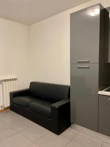a black couch in a room with a kitchen at Easy Milano - Rooms and Apartments Navigli in Milan