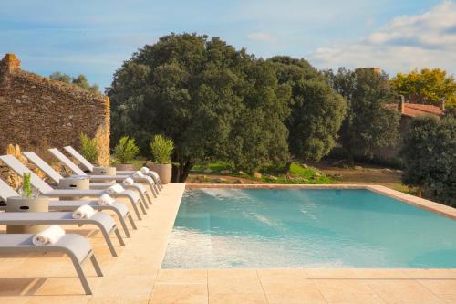 a row of lounge chairs next to a swimming pool at Mas Oms in Montnegre