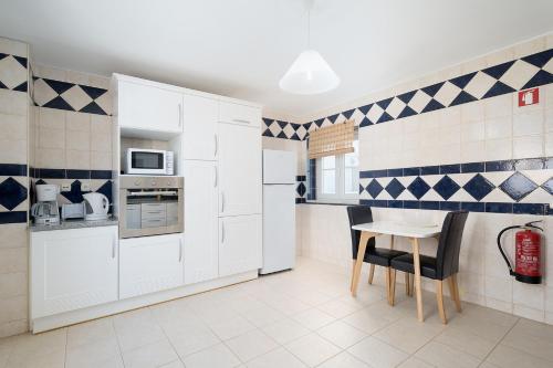 a kitchen with white cabinets and a table and chairs at Traditional Seaside Tavira Apartment in Cabanas de Tavira