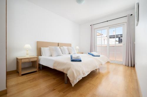 a white bedroom with a large bed and a window at Traditional Seaside Tavira Apartment in Cabanas de Tavira