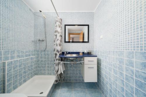 a blue tiled bathroom with a sink and a tub at Traditional Seaside Tavira Apartment in Cabanas de Tavira