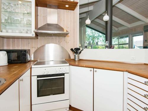 a kitchen with white cabinets and a stove at 8 person holiday home in Ebeltoft-By Traum in Ebeltoft