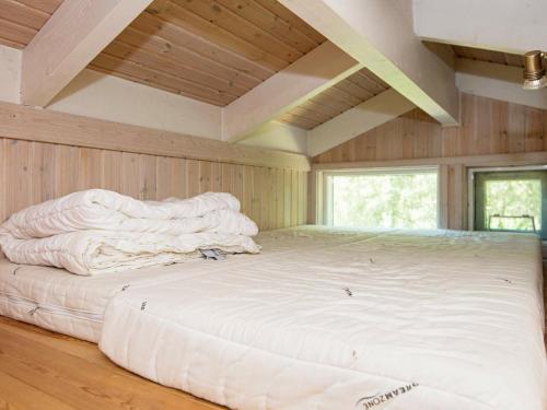 a large white bed in a room with wooden walls at 8 person holiday home in Ebeltoft-By Traum in Ebeltoft