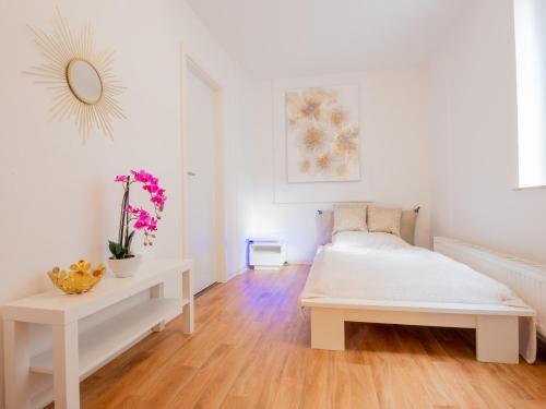 a white bedroom with a white bed and a table at EUPHORAS - Top ausgestattete Ferienwohnung mit 105 qm und 3 Schlafzimmern in Clausthal-Zellerfeld