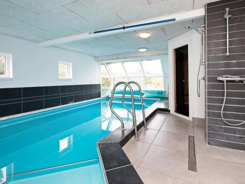 a swimming pool in a gym with blue tiles at 21 person holiday home in Bl vand in Blåvand