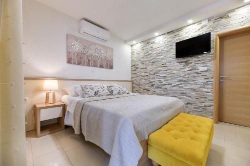 una camera con letto e TV su un muro di mattoni di Apartments Diora a Seline