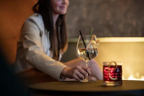 a woman sitting at a table with a glass of wine at Hotel Plan Murin in La Valle