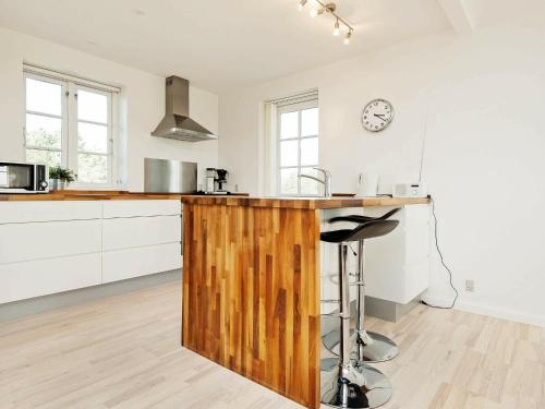a kitchen with white cabinets and a wooden counter top at 8 person holiday home in R m in Sønderby