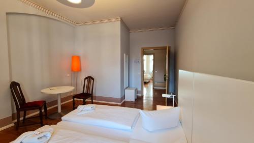 a bedroom with a white bed and a table and chair at Hotel Cranach-Herberge City Centre in Lutherstadt Wittenberg