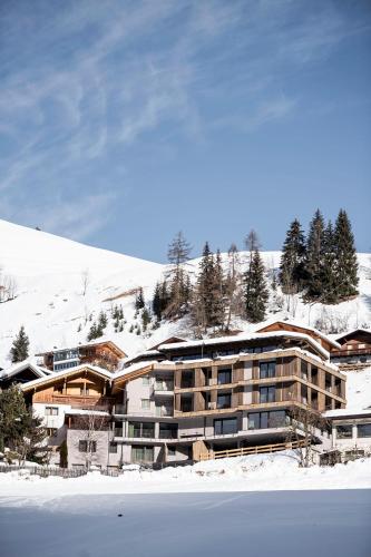 a large building in the snow next to a mountain at Hotel Plan Murin in La Valle