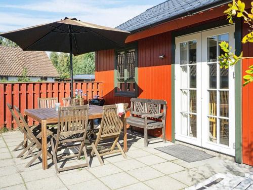 a wooden table and chairs with an umbrella on a patio at 6 person holiday home in Nex in Snogebæk