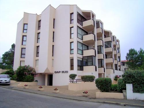 un gran edificio blanco con un coche aparcado delante de él en Appartement Pour 3 Personnes Sur Le Port -Residence Cap Sud en Capbreton