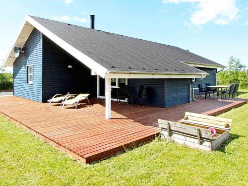 Casa con terraza de madera con mesa y sillas en 6 person holiday home in Brovst, en Brovst