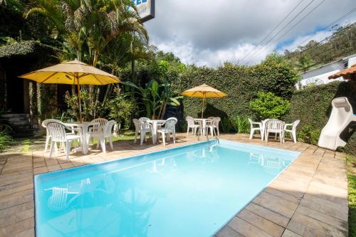 a swimming pool with tables and chairs and umbrellas at Hotel Mount Everest in Nova Friburgo