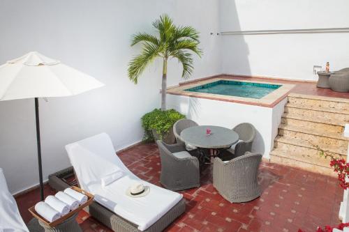 a patio with a table and chairs and a swimming pool at Hotel Casa San Agustin in Cartagena de Indias