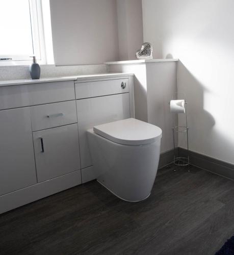 a white bathroom with a toilet and a sink at Oor Neuk in Tole