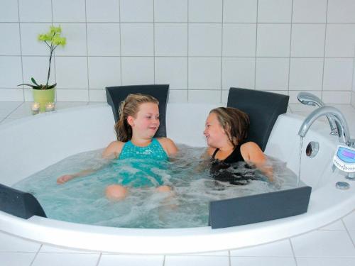 2 jeunes filles assises dans une baignoire dans l'établissement 14 person holiday home in L kken, à Løkken