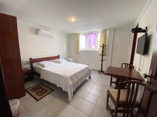 a bedroom with a bed and a table and a desk at Hotel Pousada da Praça in Recife