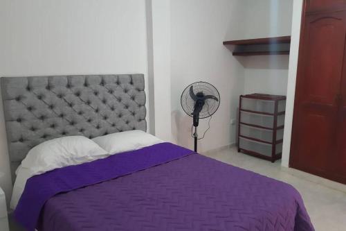 a bedroom with a purple bed and a fan at Casa Vacacional Riohacha Turística. in Ríohacha