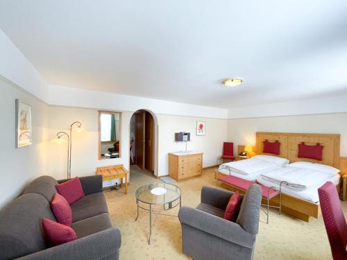 a living room with a bed and two couches at Boutique Hotel Engadinerhof - A Home for Generations in Pontresina