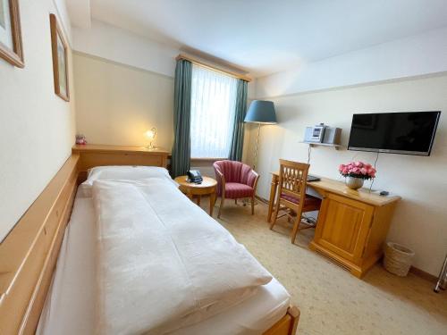 a hotel room with a bed and a desk at Boutique Hotel Engadinerhof - A Home for Generations in Pontresina