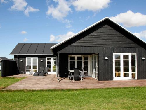 a black house with a deck and a patio at 8 person holiday home in Nysted in Nysted