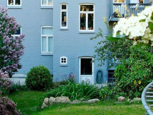a blue house with a white door in a yard at 4 person holiday home in S nderborg in Sønderborg