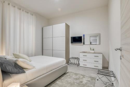 a white bedroom with a bed and a dresser at Tourist Apartment Civitavecchia in Civitavecchia