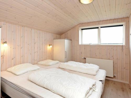 two beds in a room with wooden walls and a window at Four-Bedroom Holiday home in Rømø 5 in Rømø Kirkeby