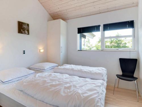 a bedroom with two beds and a chair and a window at Three-Bedroom Holiday home in Hemmet 52 in Hemmet