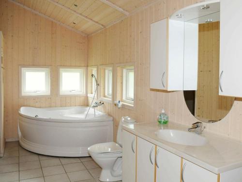 uma casa de banho com uma banheira, um WC e um lavatório. em Three-Bedroom Holiday home in Oksbøl 17 em Oksbøl